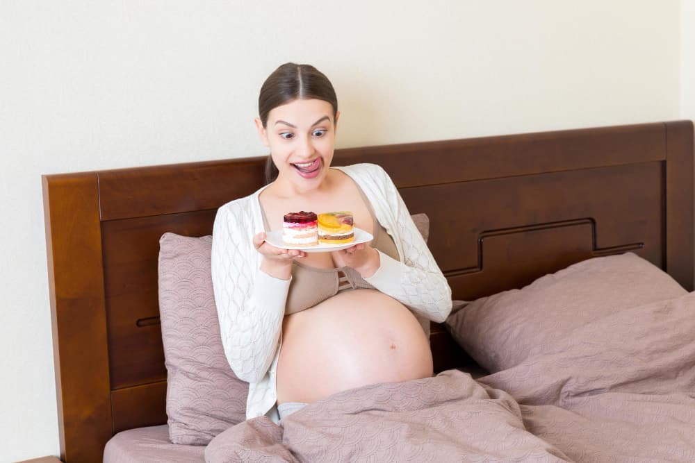 Une femme enceinte excitée mange des gâteaux