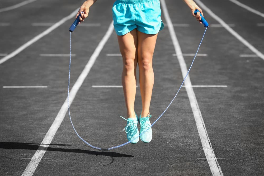 Jeune femme sautant à la corde au stade