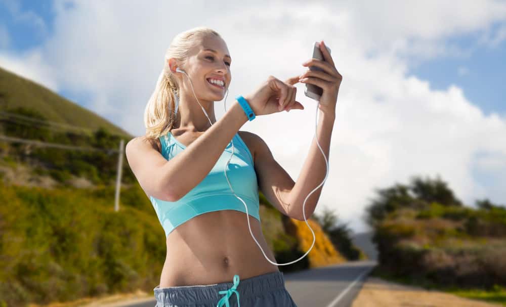Femme avec un smartphone et des écouteurs faisant du sport