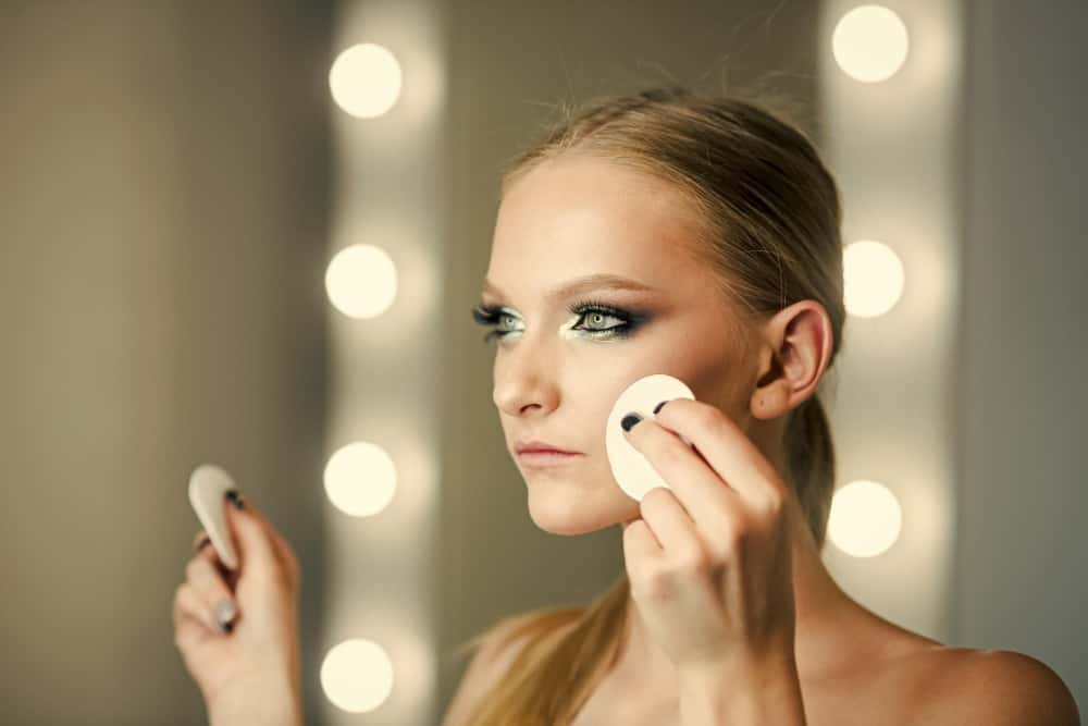 Femme utilisant un coton sur le visage