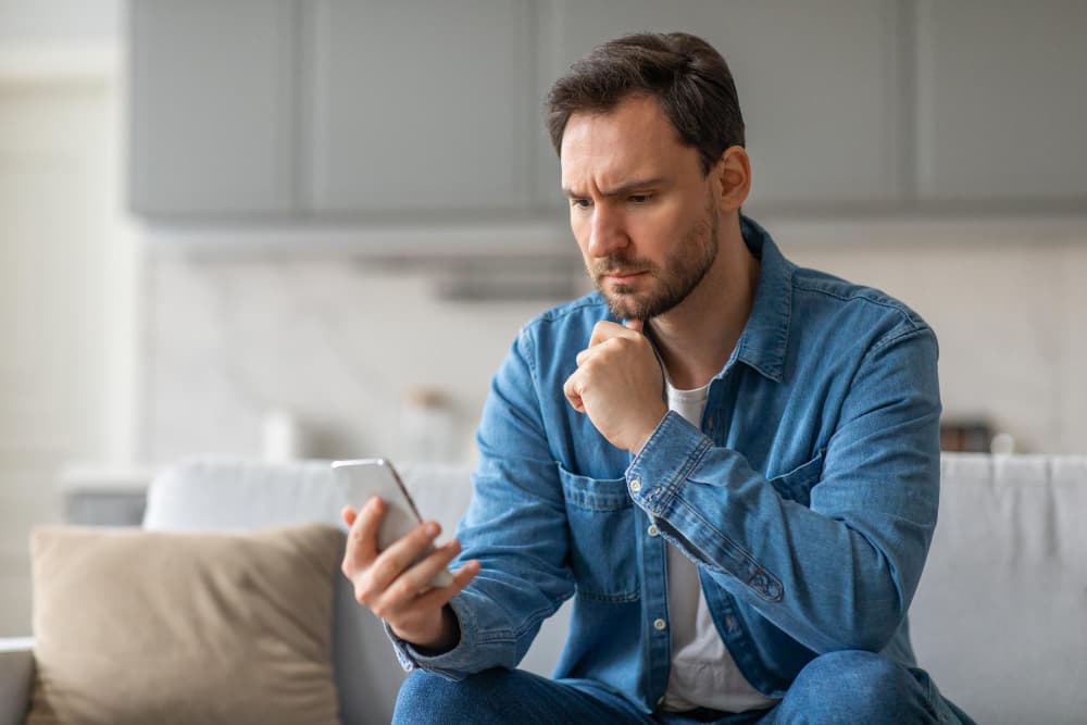 Un homme préoccupé lit son smartphone